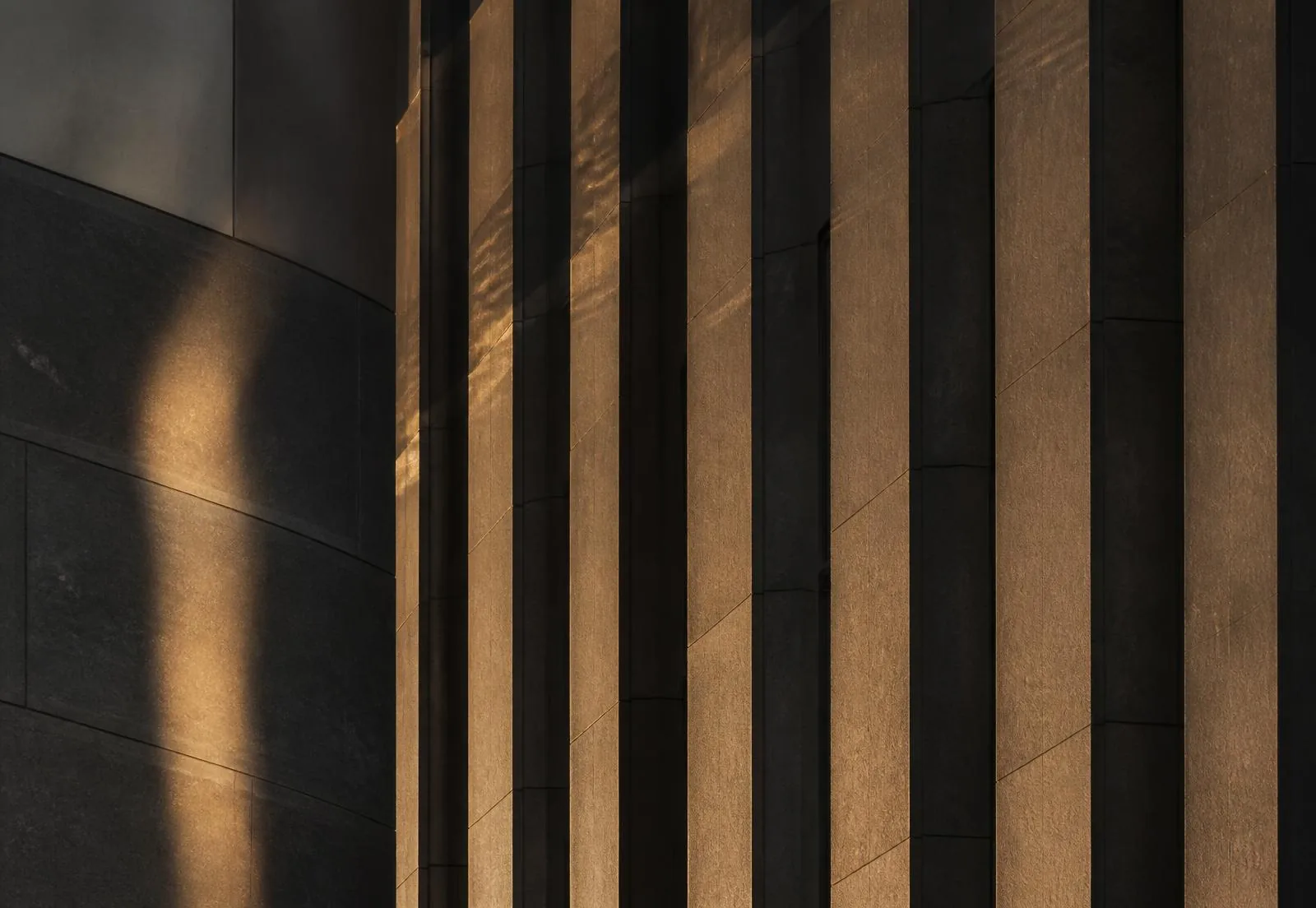 Providence Equity LLC — considered stewardship of capital Dark stone facade of a financial district building with warm light falling across its vertical fins